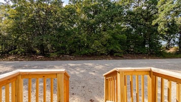 Ein Kiesparkplatz mit Holzzäunen und üppigem Grün im Hintergrund.