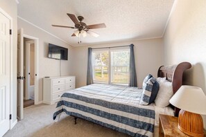 A bedroom with a bed, a ceiling fan, a TV, a dresser, and a window with curtains. - Big Lake, No Schedule | Sleeps 8 | Pet Friendly (Kingston)
