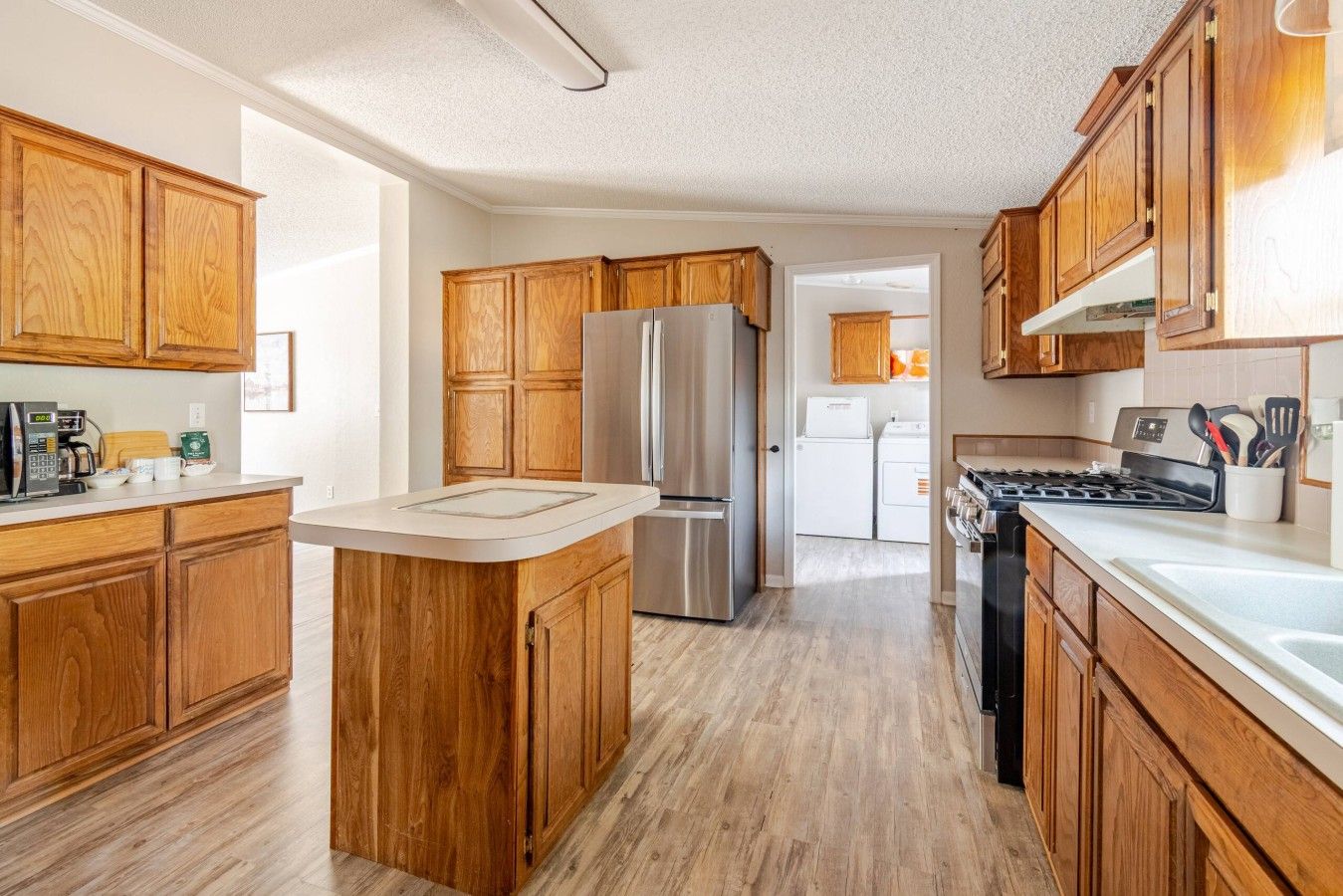 Una cocina con armarios de madera, un refrigerador de acero inoxidable y una estufa.