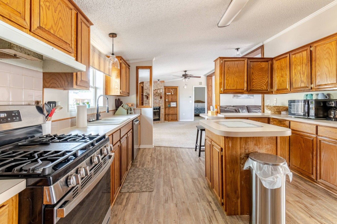 Una cocina moderna con armarios de madera, estufa de acero inoxidable y una isla central.