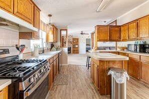 Een moderne keuken met houten kastjes, een roestvrijstalen fornuis en een centraal eiland.
