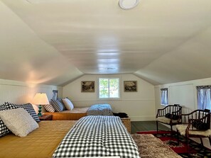 A bedroom with two beds, a window, a lamp, and a chair.