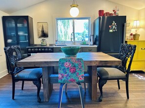 A kitchen with a wooden table, two chairs, a stove, a sink, and a refrigerator.