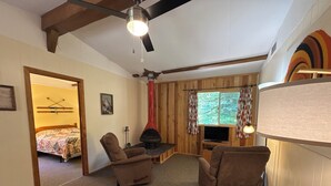 A cozy room with a bed, two sofas, a wooden coffee table, a fireplace, and a television.