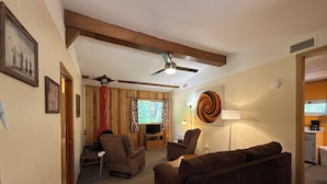 A living room with a fireplace, ceiling fan, and a large spiral artwork on the wall.