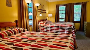 A hotel room with two beds, a wooden headboard, a lamp, a ski-themed wall decoration, and a window with curtains.
