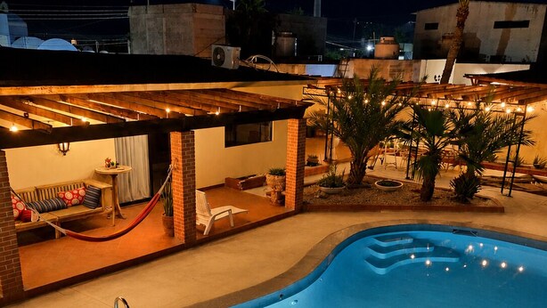 A swimming pool with a wooden deck area, a hammock, and a small seating area with cushions. - Family home with private pool, loft and garage, super central location! (La Paz)