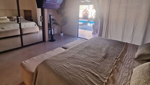A bedroom with a bed, a ceiling fan, a TV, and a view of a pool. - Family home with private pool, loft and garage, super central location! (La Paz)
