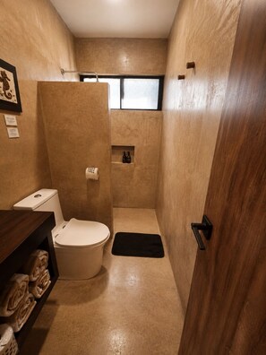 Ein kleines Badezimmer mit Toilette, Duschkabine und Ablage für Toilettenartikel.