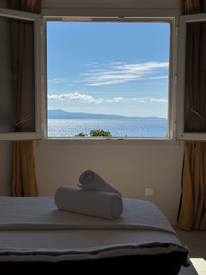 Ein Zimmer mit Bett, einem Vorhangfenster und Meerblick.