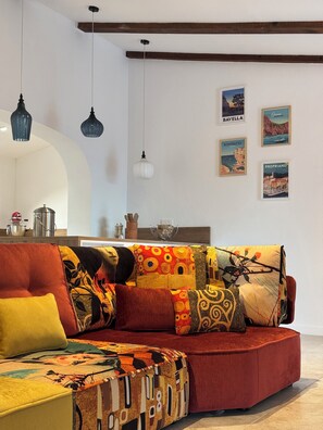 Ein modernes Wohnzimmer mit einem roten Sofa, bunten Kissen und hängenden Pendelleuchten.