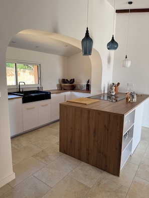 Eine moderne Küche mit einer zentralen Holztheke, einem Spülbecken und zwei Pendelleuchten.