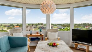 A room with a large window, a television, a table with fruit, and a lamp. - "Nyyrikki" - 350m from the sea by Interhome (Ringkøbing)