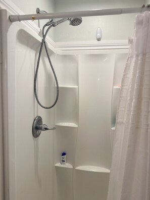 Eine Dusche mit Duschkopf, Handbrause und Seifenspender.