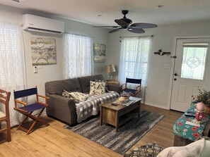 A living room with a sofa, two chairs, a coffee table, a ceiling fan, and a door with a window. - Emma's Casa Bonita; Cozy Coastal Cottage Near Rockport Attractions (Rockport)