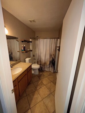 Un baño con lavamanos, inodoro y cortina de ducha.