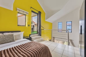 Ein Schlafzimmer mit Bett, Fenster, Treppe und Blick ins Freie.