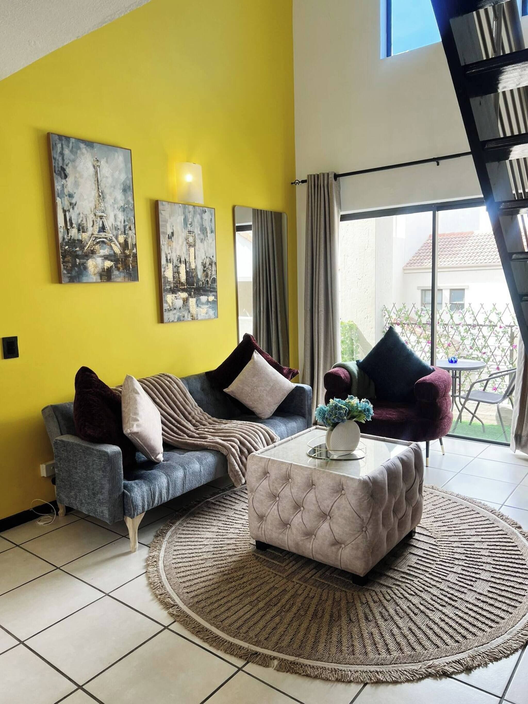 A living room with a sofa, ottoman, and two paintings on the wall.