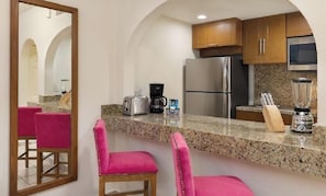 Una cocina con encimeras de granito, electrodomésticos de acero inoxidable y taburetes de bar rosados.