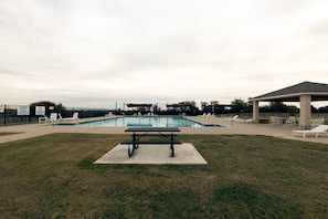 Ein Swimmingpool mit Liegestühlen, einem Picknicktisch und einem überdachten Pavillon.