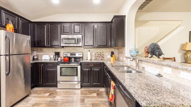 A modern kitchen with dark cabinets, stainless steel appliances, granite countertops, and a visible staircase. - 4-bedroom/3 bath house in brilliant Georgetown with cool AC. (Georgetown)