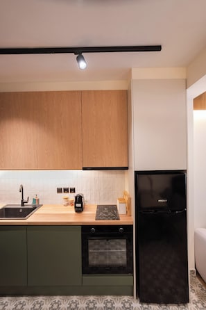 Una cocina moderna con armarios de madera, un refrigerador negro y salpicadero de azulejos.