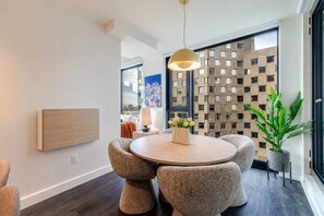 Un comedor moderno con una mesa redonda, sillas acolchadas, una lámpara colgante y una planta decorativa.