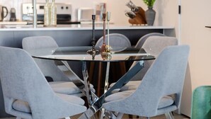 A modern dining area with a round table, grey upholstered chairs, and a unique metal base. - Modern Downtown Stay | Pool & Skyline (Montreal)