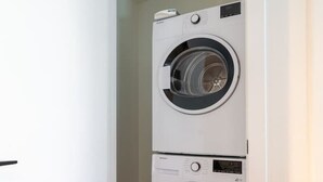 A laundry room with two stacked front-loading washing machines. - Modern Downtown Stay | Pool & Skyline (Montreal)