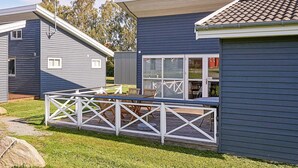 A modern, single-story building with a covered patio area, a fenced deck, and a small outdoor seating area. - 6 Person Holiday Park Home in Gudhjem (Gudhjem)