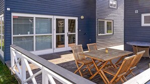 A deck with wooden furniture and a white railing. - 6 Person Holiday Park Home in Gudhjem (Gudhjem)