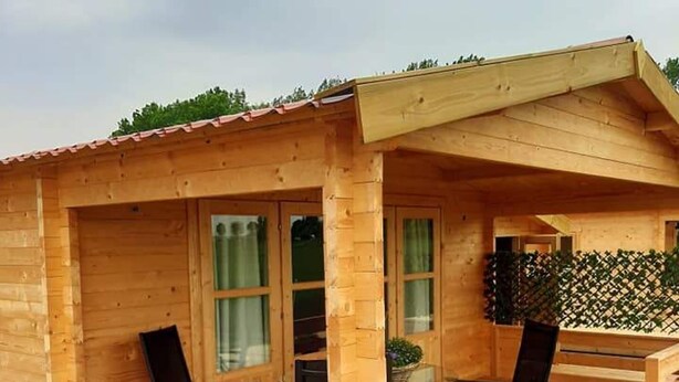 Una cabaña de madera con un balcón, una mesa y sillas.