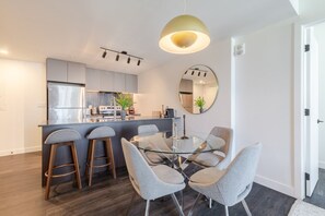 A modern kitchen with a central island, bar stools, and a round dining table with chairs. - Stylish Downtown Retreat | Pool & Views (Montreal)