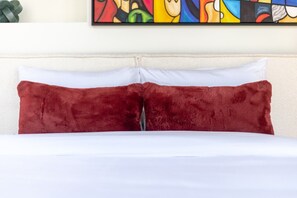 A bed with white sheets and two red pillows. - Stylish Downtown Retreat | Pool & Views (Montreal)