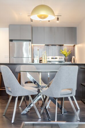 A modern kitchen with a central island, grey chairs, and a pendant light. - Premium Downtown Living | Pool Gym & Views (Montreal)