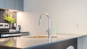 Cozinha moderna com torneira de aço inoxidável, forno embutido e máquina de café.