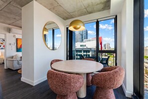 A modern dining area with a round table, two patterned chairs, a large mirror, and a pendant light. - Chic Urban Retreat | Pool Gym & Terrace (Montreal)