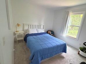 A bedroom with a bed, nightstand, lamp, window, and a small plant. - Serene 4-bedroom and 2.5 bathroom house charming Rockford (Rockford)