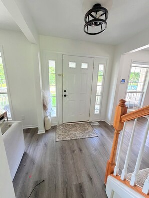 A clean, well-lit entryway with a wooden floor, a white door, and a staircase with white railings. - Serene 4-bedroom and 2.5 bathroom house charming Rockford (Rockford)