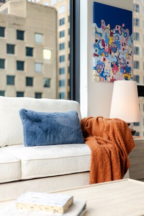 A modern living room with a sofa, a blue pillow, a brown throw blanket, and a lamp. - Luxe Central Retreat | Free Parking & Pool (Montréal)