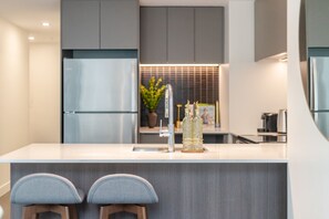 A modern kitchen with a central island, stainless steel appliances, and a potted plant. - Luxe Central Retreat | Free Parking & Pool (Montréal)