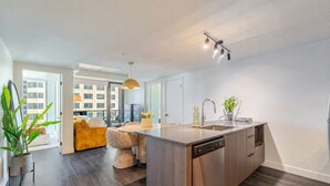 A modern kitchen with a central island, built-in dishwasher, and a view to the outside. - Luxury Stay | Free Parking (Montréal)
