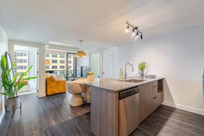 A modern kitchen with a central island, built-in dishwasher, and a view to the outside. - Luxury Stay | Free Parking (Montréal)