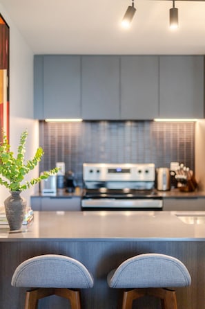 Eine moderne Küche mit einer zentralen Kochinsel, Barhocker und einem Blumentopf.