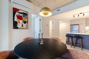 A modern kitchen with a central island, bar stools, and a dining table with candles. - Downtown Poolside Retreat | Free Parking & Pool (Montréal)