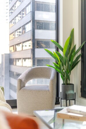 A modern living room with a textured armchair, a potted plant, and a glass coffee table. - Modern Montreal Escape | Pools Gym Cinema Balcony (Montreal)