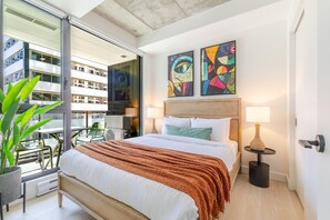 A hotel room with a bed, two bedside lamps, a window with a view of buildings, and two abstract paintings on the wall. - Modern Montreal Escape | Pools Gym Cinema Balcony (Montreal)