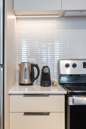 A kitchen with a kettle, a coffee maker, and an oven. - Modern Montreal Escape | Pools Gym Cinema Balcony (Montreal)