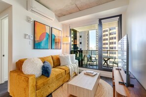 A modern living room with a sofa, a coffee table, and a balcony with chairs. - Modern Escape | Free Parking & Rooftop Pool (Montréal)
