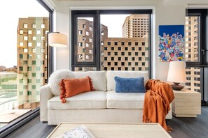 A modern living room with a sofa, pillows, a lamp, and a painting. - Urban Oasis Balcony Stay | Free Parking & Pool (Montréal)